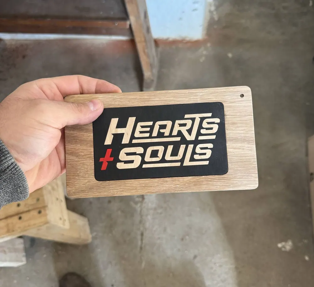 A laser-cut sign of the Hearts and Souls logo.