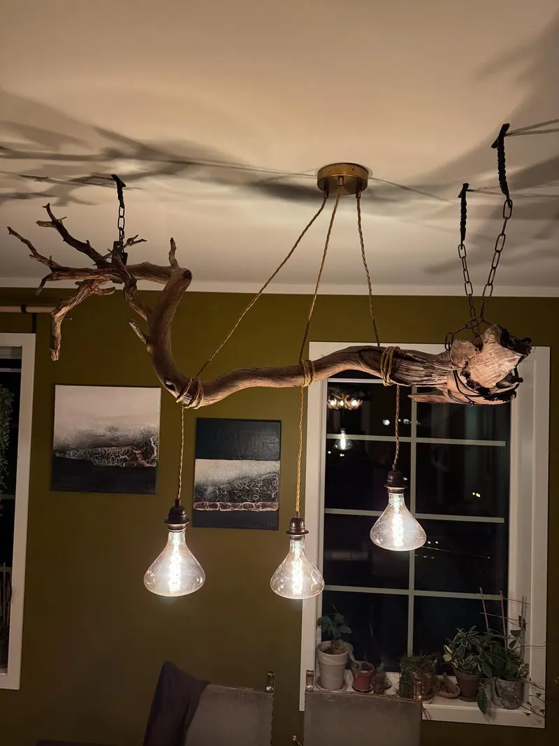 A completed wooden branch light fixture hanging from its brackets.